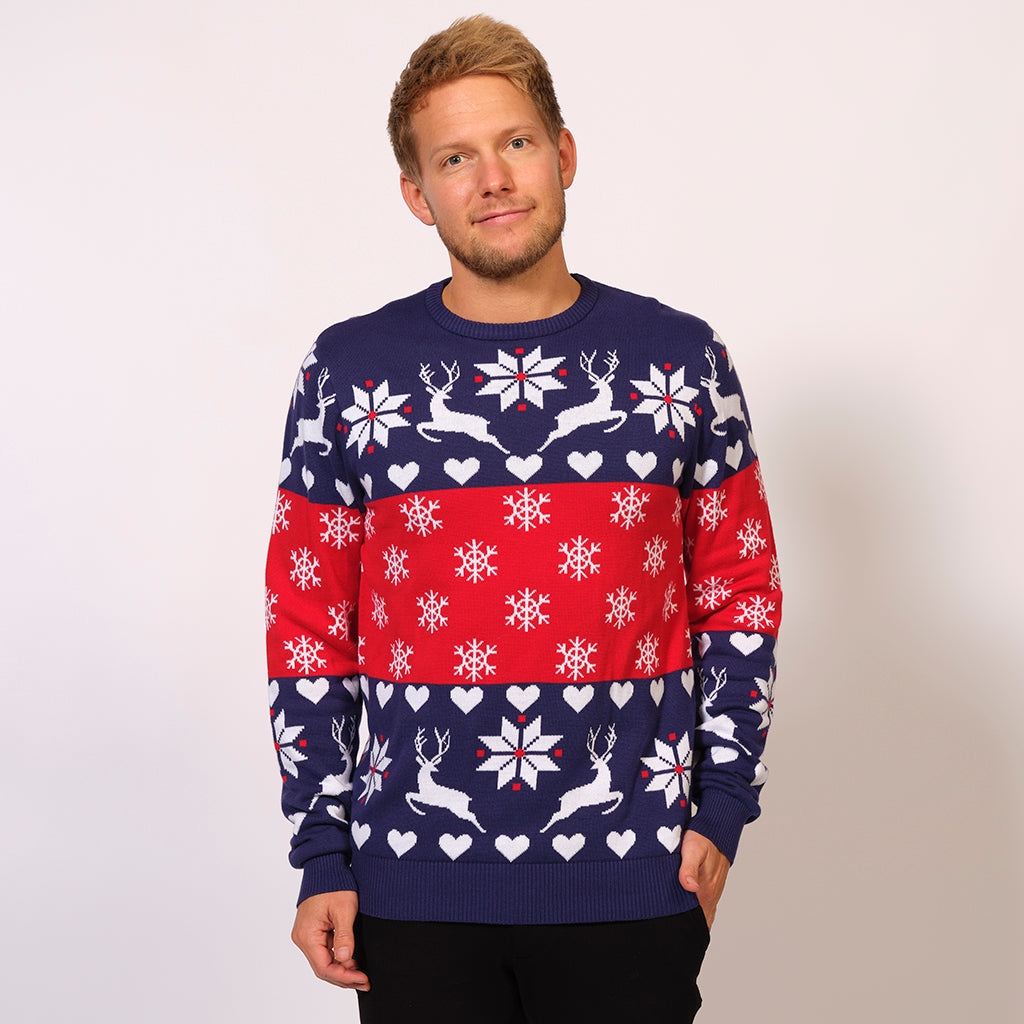 En mand står i en julesweater med snefnug og rensdyr på.
